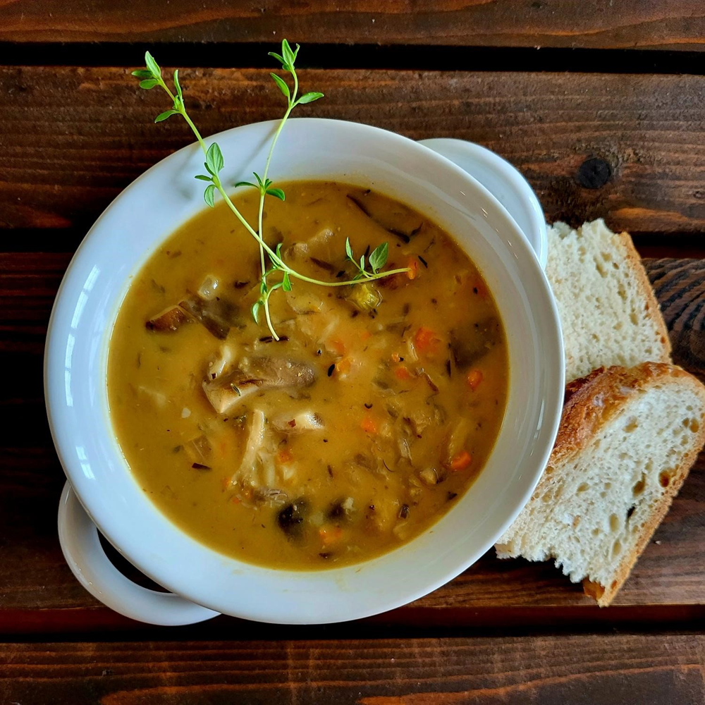  bowl of soup with bread on a wooden surface