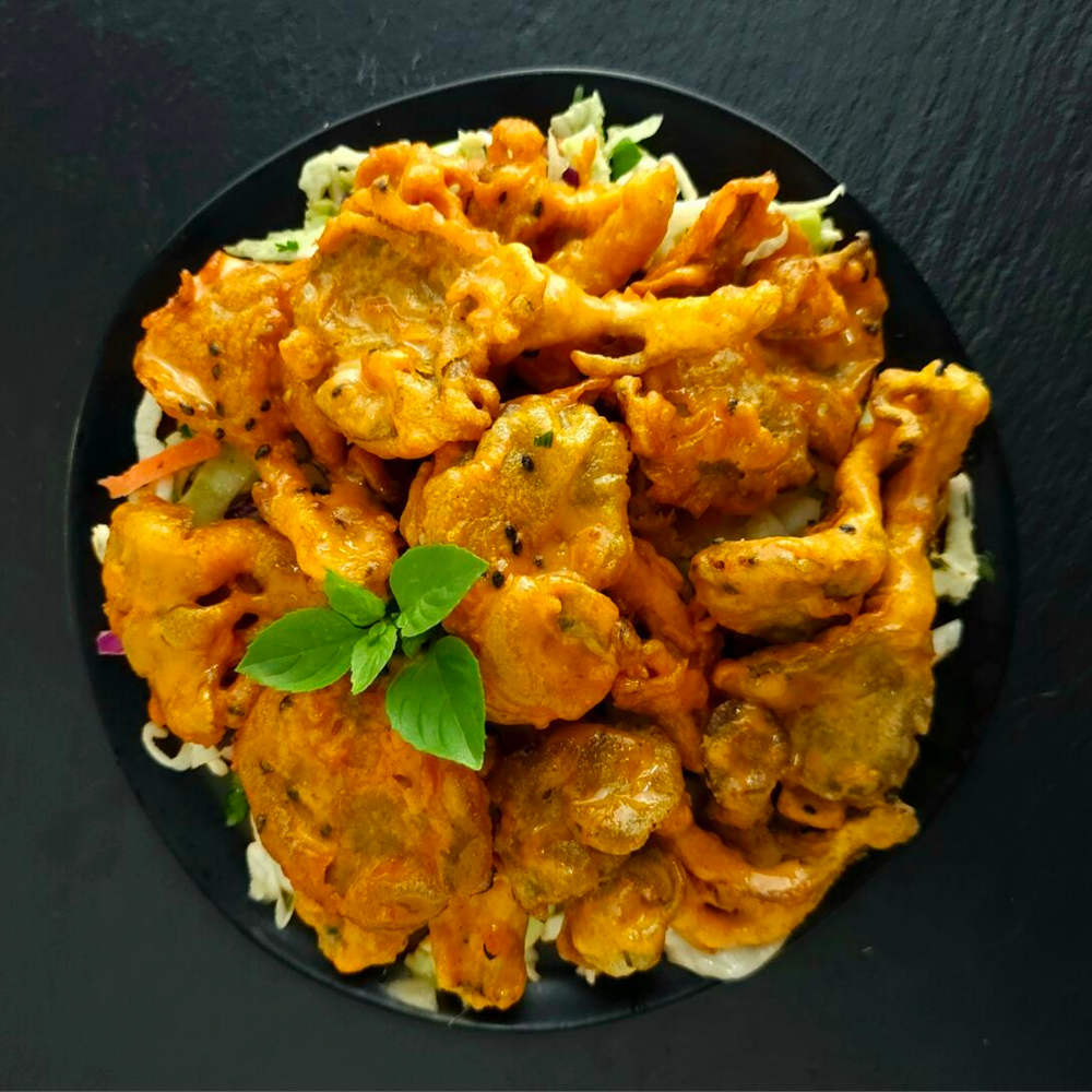 Fried cauliflower with a red sauce on a black plate