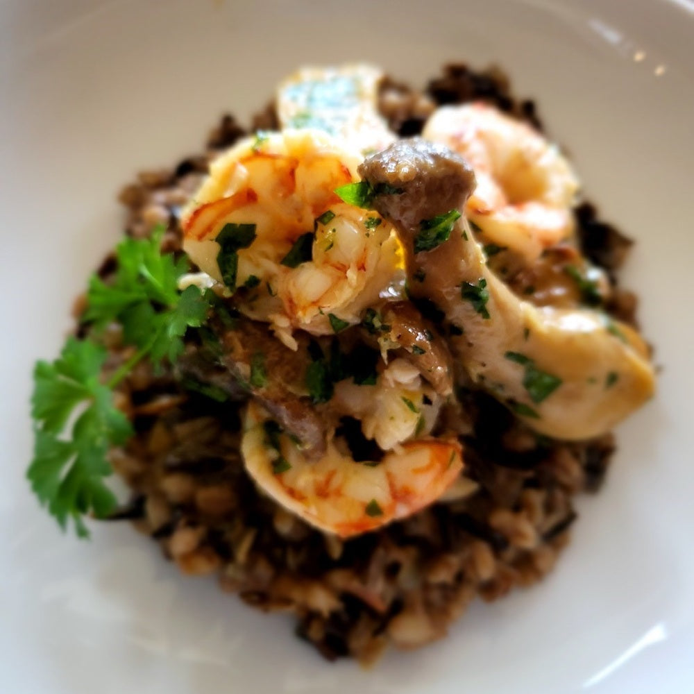 Plated dish with shrimp and mushroom on a bed of dark rice